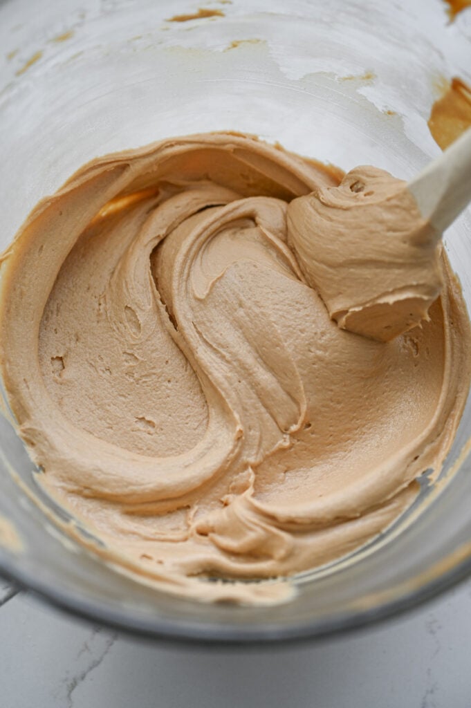 A bowl with a light tan colored frosting in it.