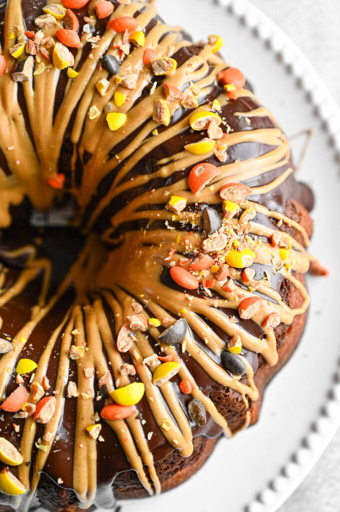 The overhead view of a bundt cake topped with a chocolate glaze, a peanut butter drizzle and chopped peanut butter candies.