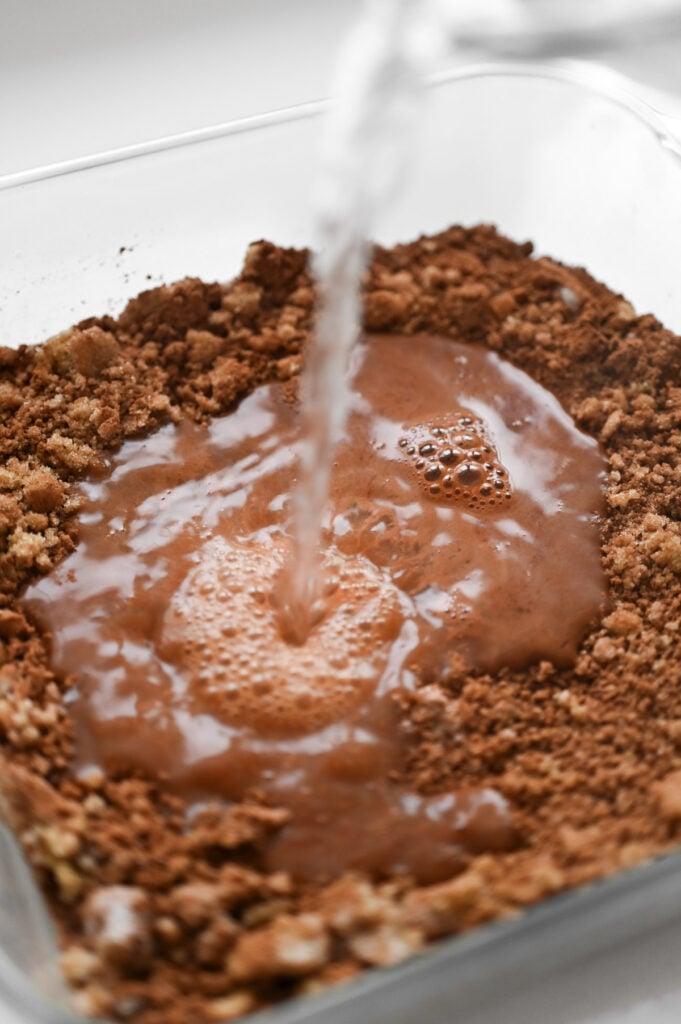 Hot water being poured into a dry chocolatey mixture.