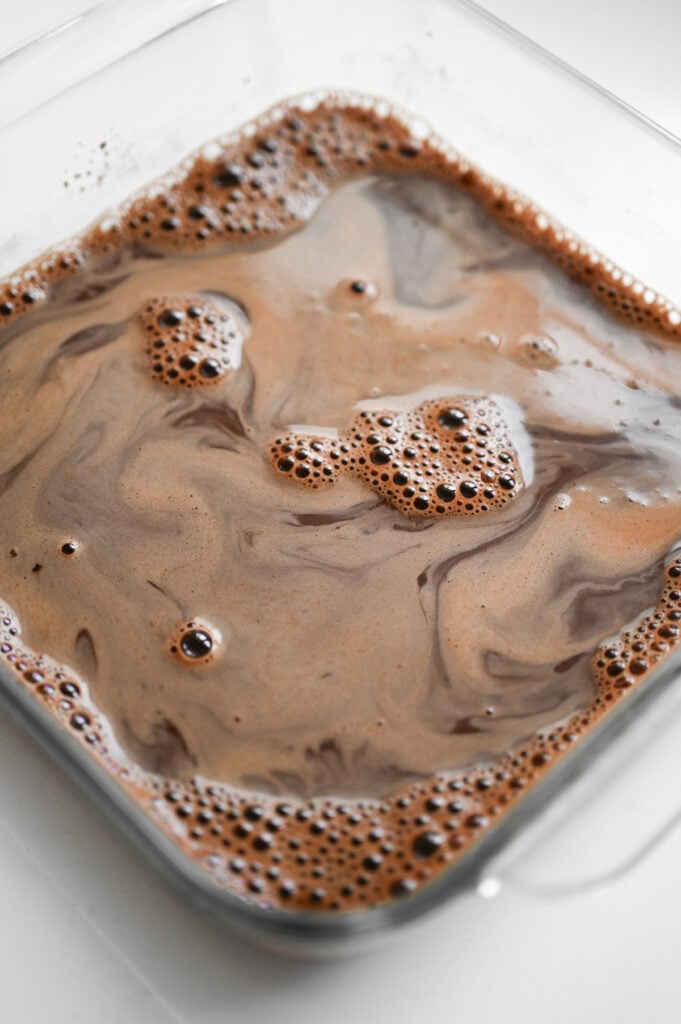 A warm chocolate liquid in a square baking dish.