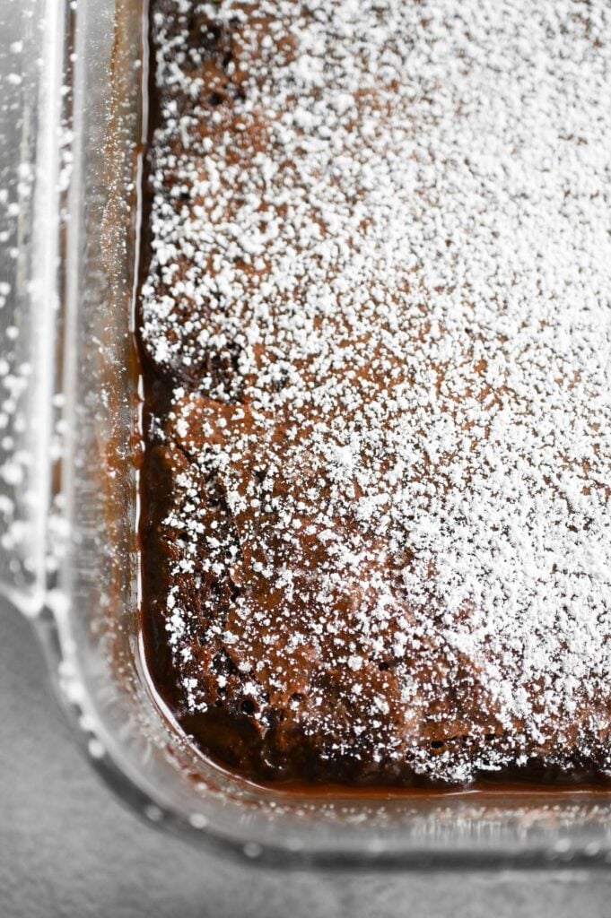Close-up of a pan of brownie cobbler with a dusting of powdered sugar on top.