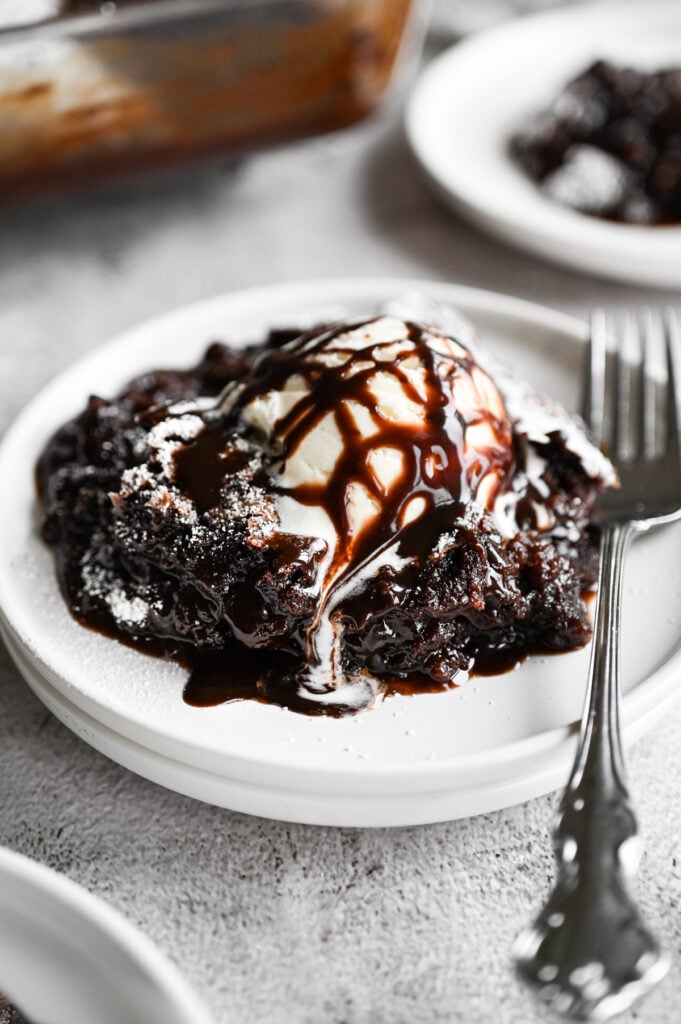 Vanilla ice cream melting on top of a big scoop of brownie cobbler that looks super fudgy and decadent.