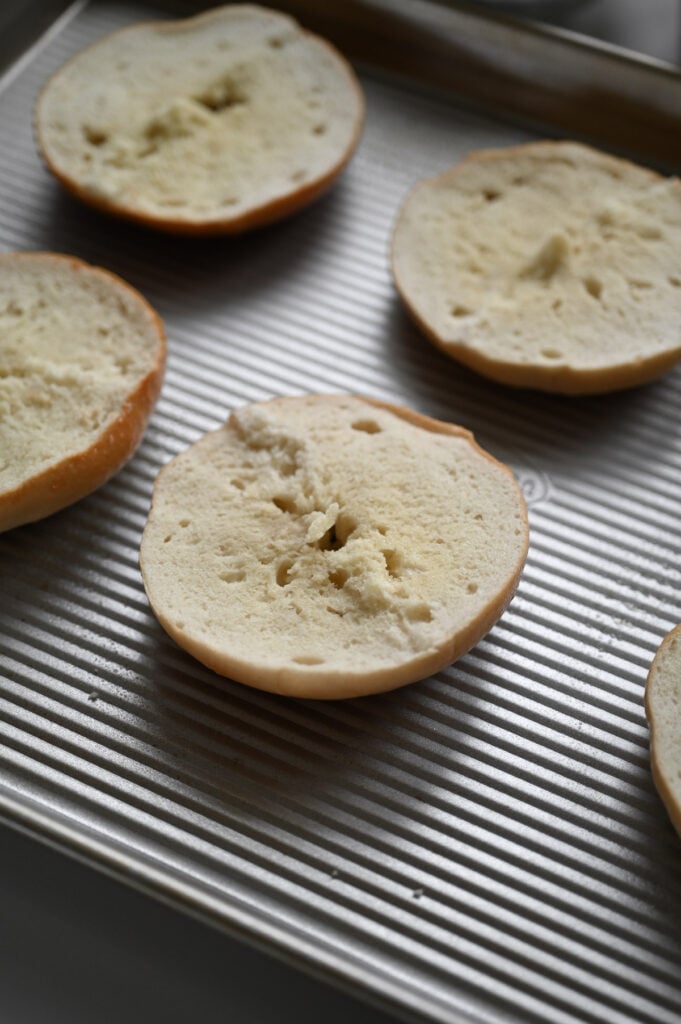 Sliced bagels on a sheet pan; cut-side-up.