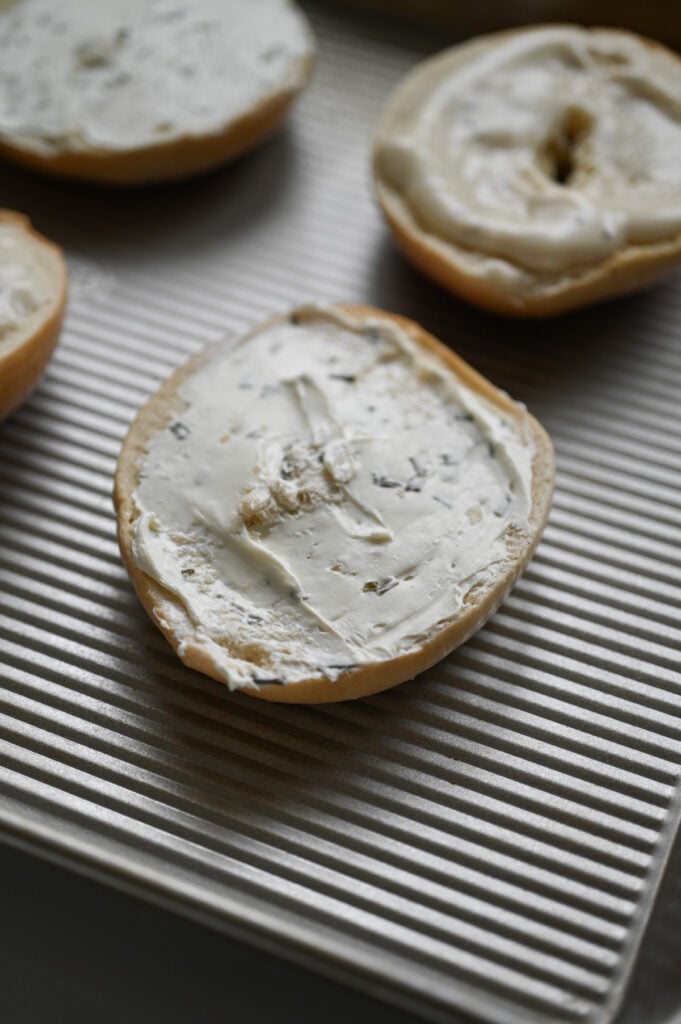 A bagel with onion and chive cream cheese spread on top.