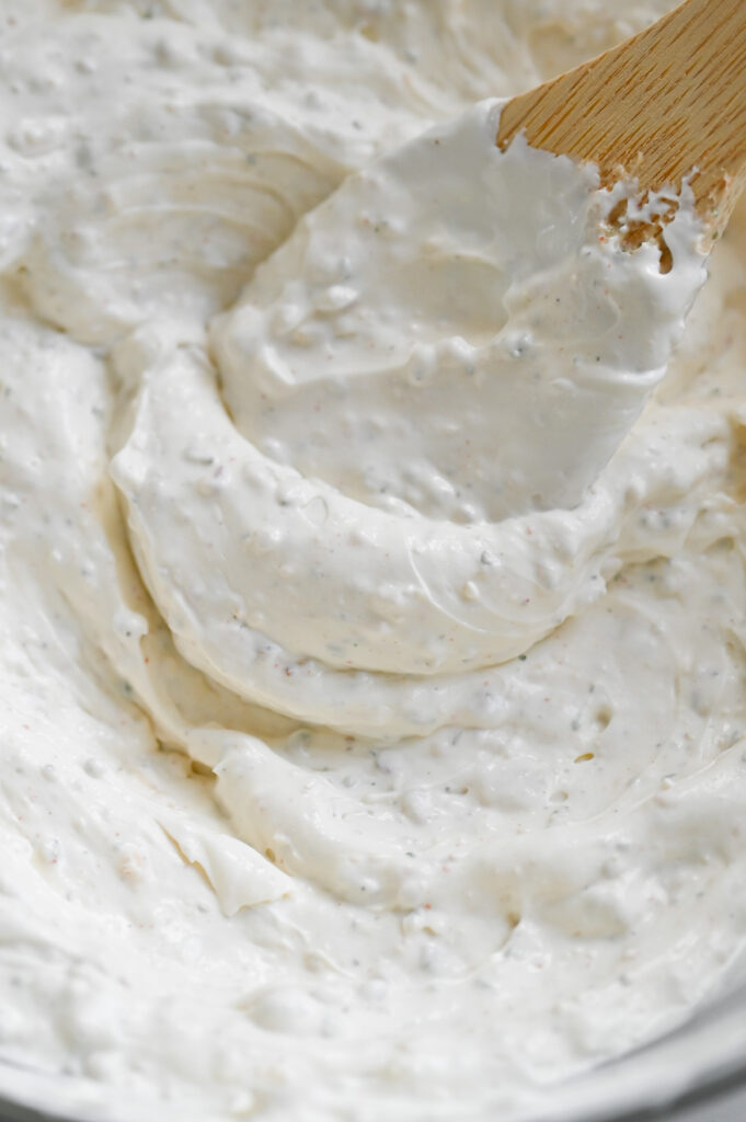 A creamy dip being stirred in a bowl.