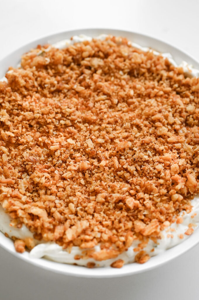 A bowl with dip topped with crunchy French fried onion crumbs.