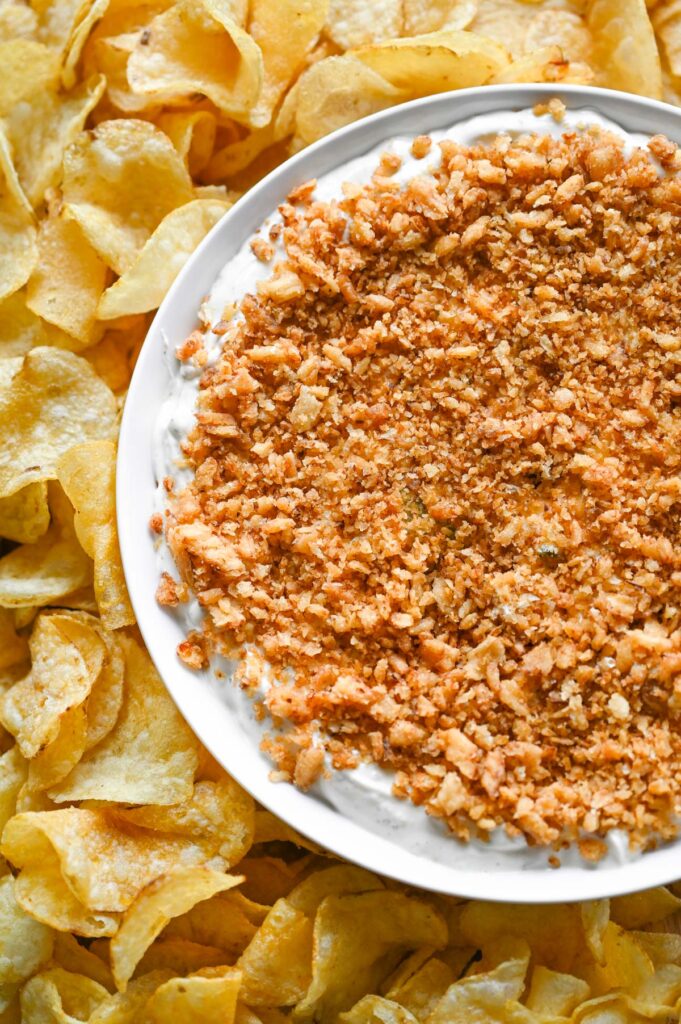 Fried pickle dip in a round bowl with kettle-cooked potato chips around it.