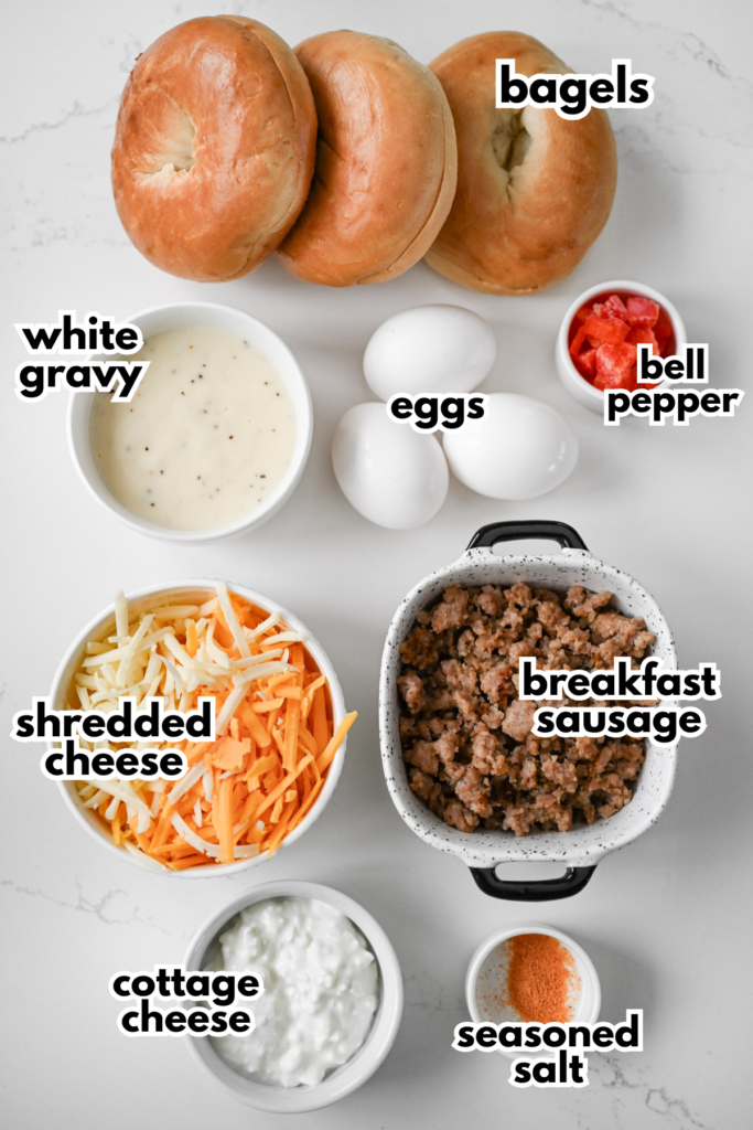 The ingredients needed to make breakfast pizza bagels all laid out on a white countertop with labels.