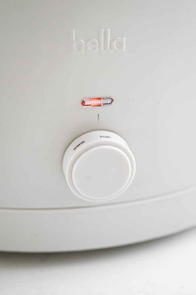 A slow cooker with the knob turned to "high."