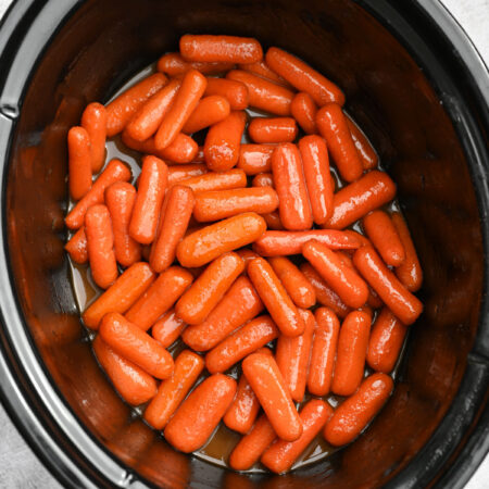 A slow cooker crock with carrots in it.
