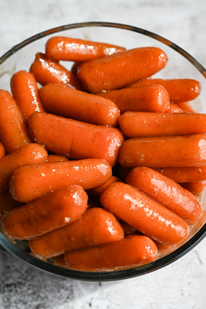Glazed baby carrots in a glass bowl for storage.