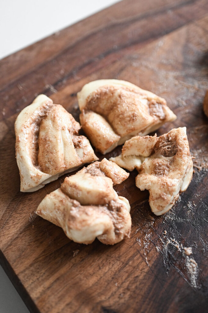 A thawed cinnamon roll being cut into 4 pieces.