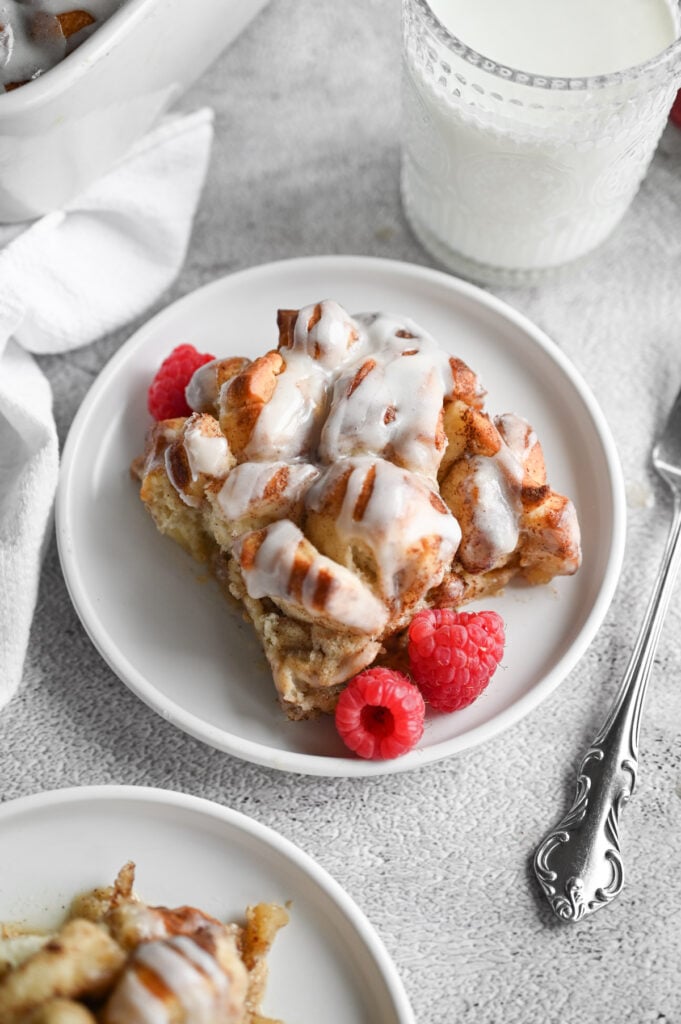 Cinnamon roll casserole with frosting on top and raspberries on the side.