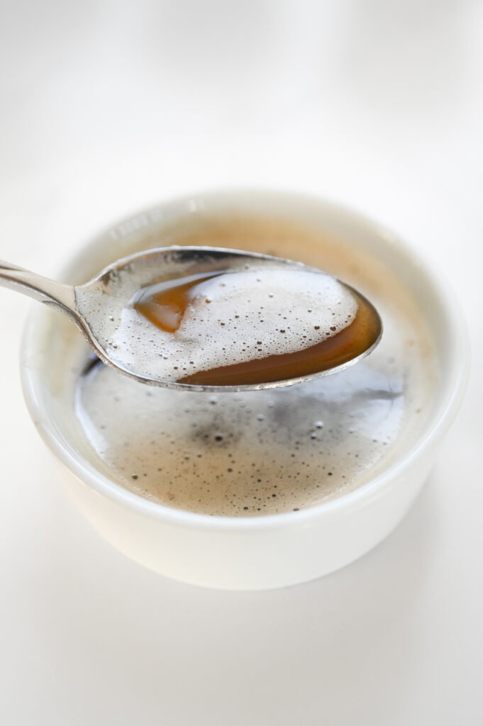 A white bowl with browned butter; a spoon is full of browned butter to show the color.