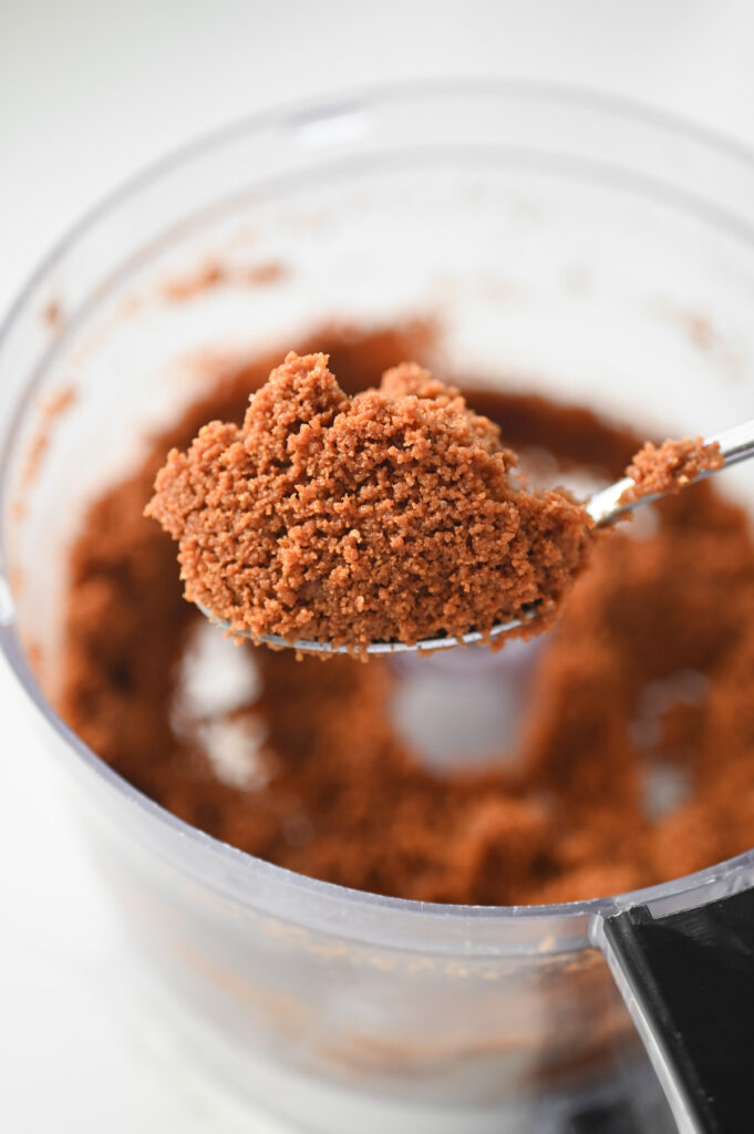 Biscoff cookie crumbs mixed with melted butter on a spoon.