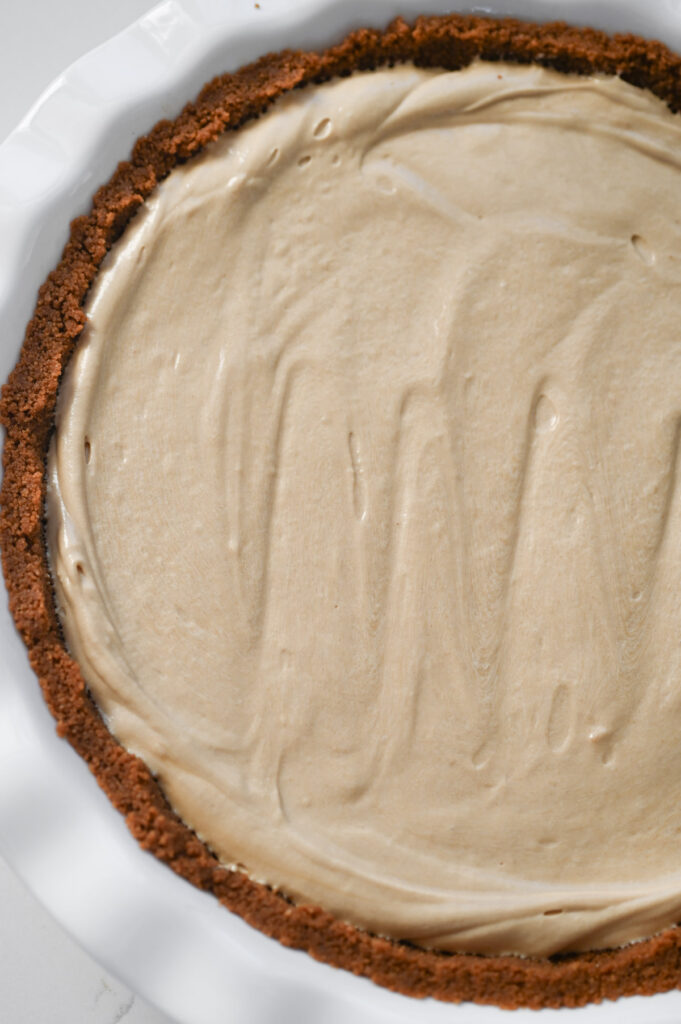A brown pie crust with a creamy filling inside of it; smoothed out on top.