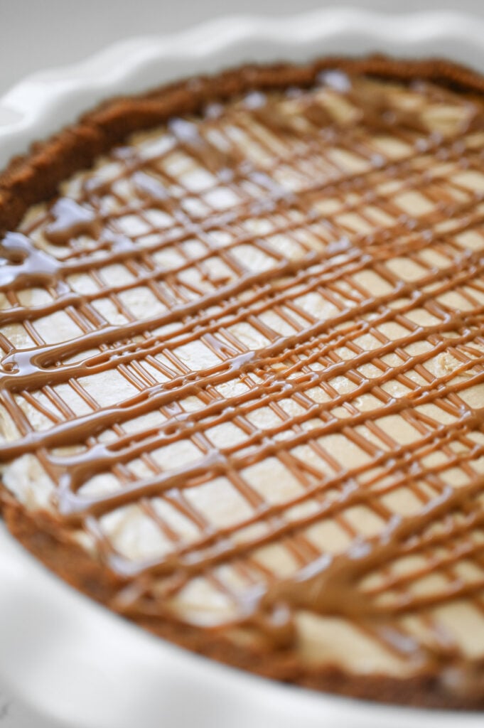 A pie with a drizzle of cookie butter on top.