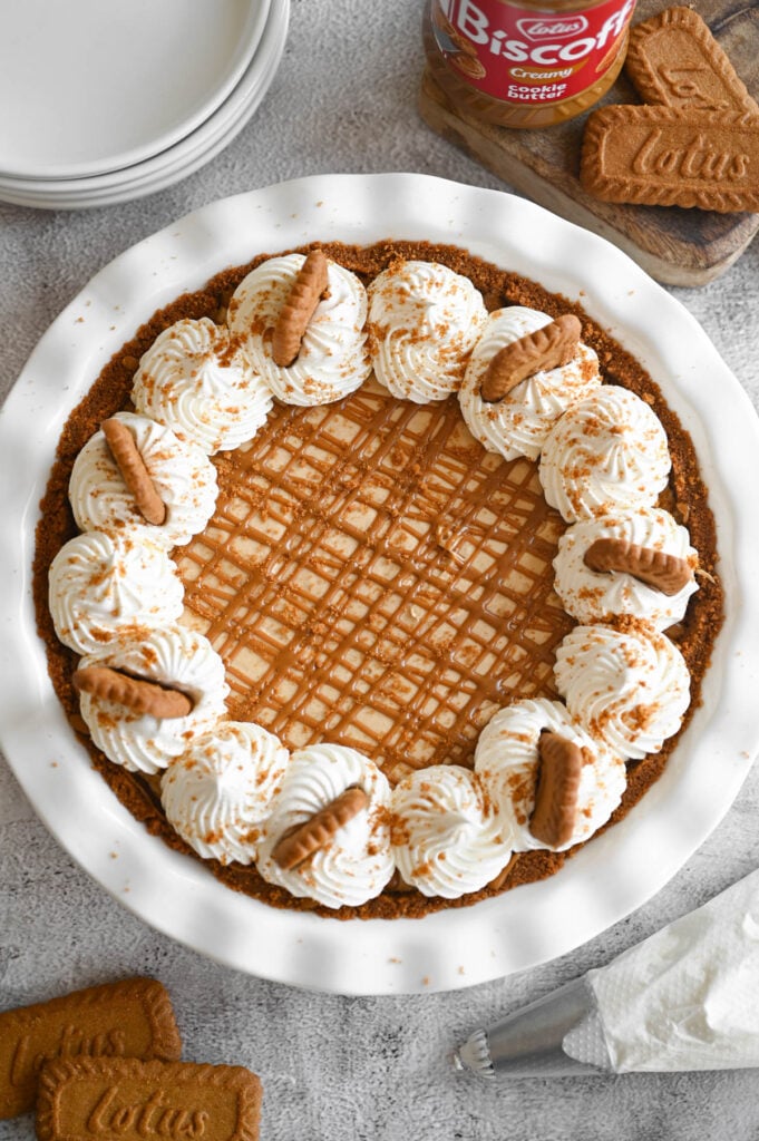 The overhead picture of a Biscoff pie that's been garnished with creamy Biscoff spread, whipped cream dollops, Biscoff cookie crumbs and cookies pressed into the dollops of whipped cream.