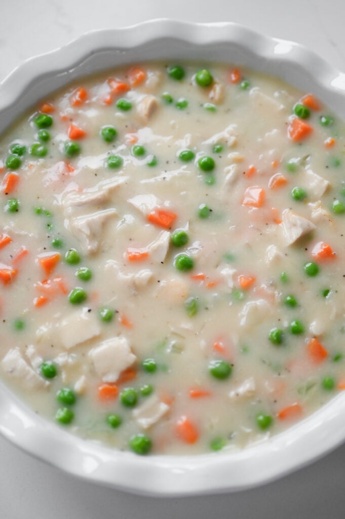Chicken pot pie filling in a white pie plate.