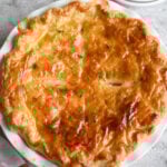 Puff Pastry Chicken Pot Pie with a shiny, flaky golden brown topping in a white ceramic pie plate.
