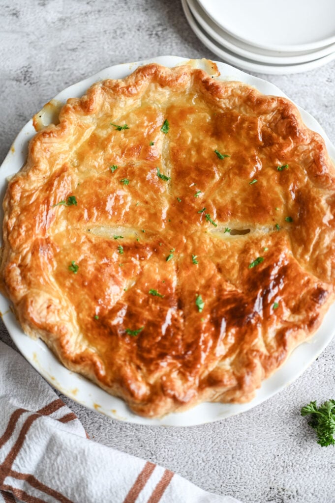 A baked chicken pot pie with a golden brown puff pastry on top.