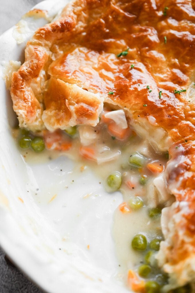 A pie plate with pot pie; a scoop taken from it.