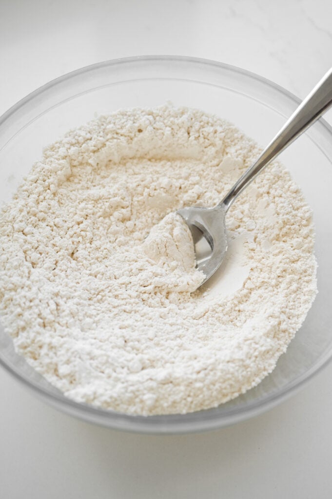 Dry ingredients of a cake stirred up in a clear bowl.