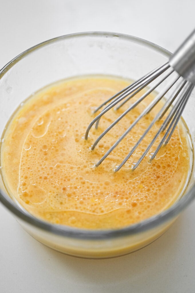 Eggs, oil and vanilla whisked together in a clear bowl.