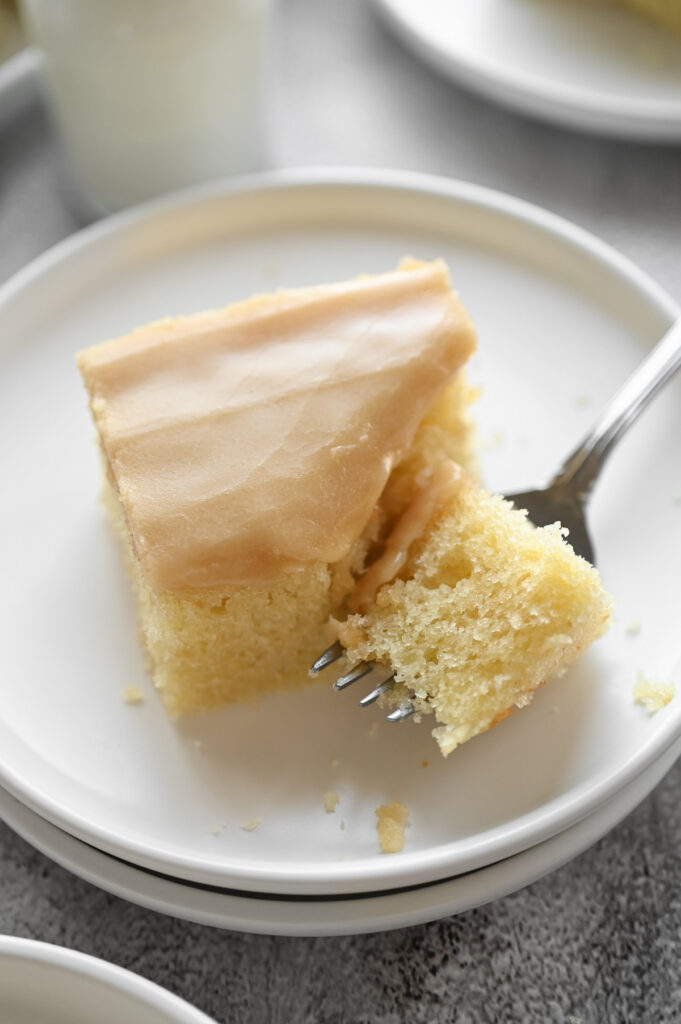 A fork taking a bite out of a square piece of cake.