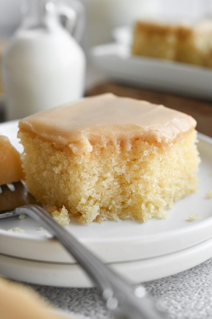 A piece of frosted buttermilk cake with a bite out of it.