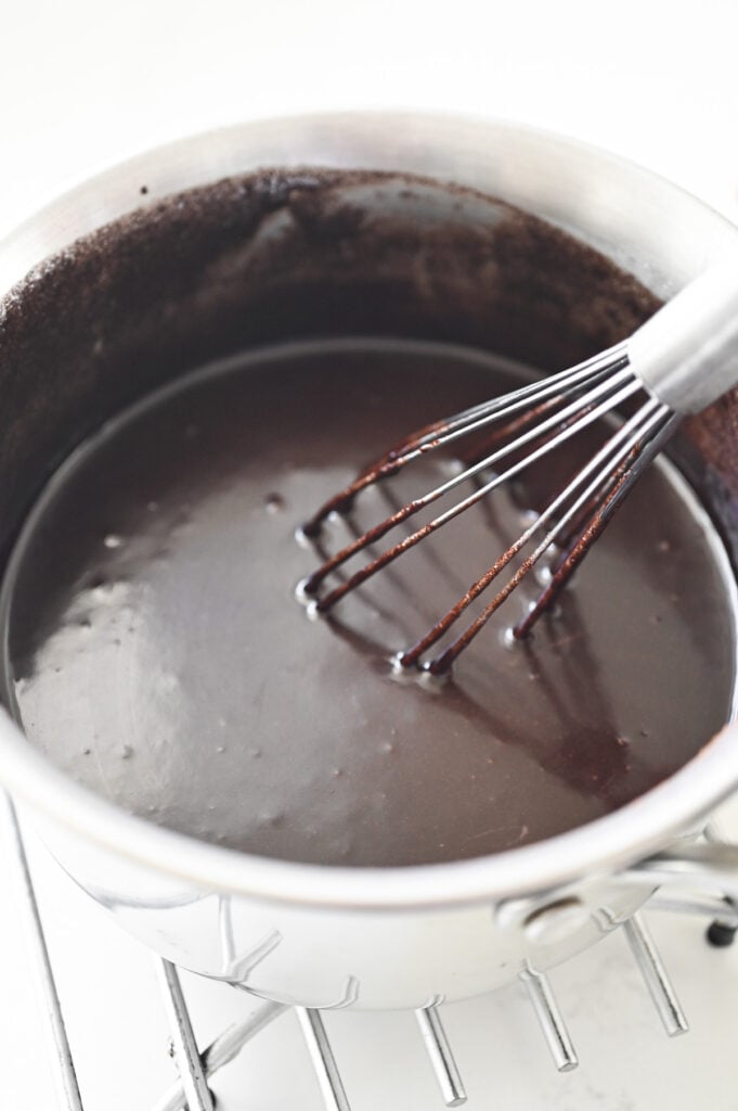 A whisk combining a chocolate-y mixture.