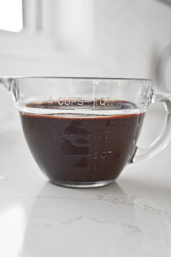 A measuring glass with 3 cups of chocolate frosting.
