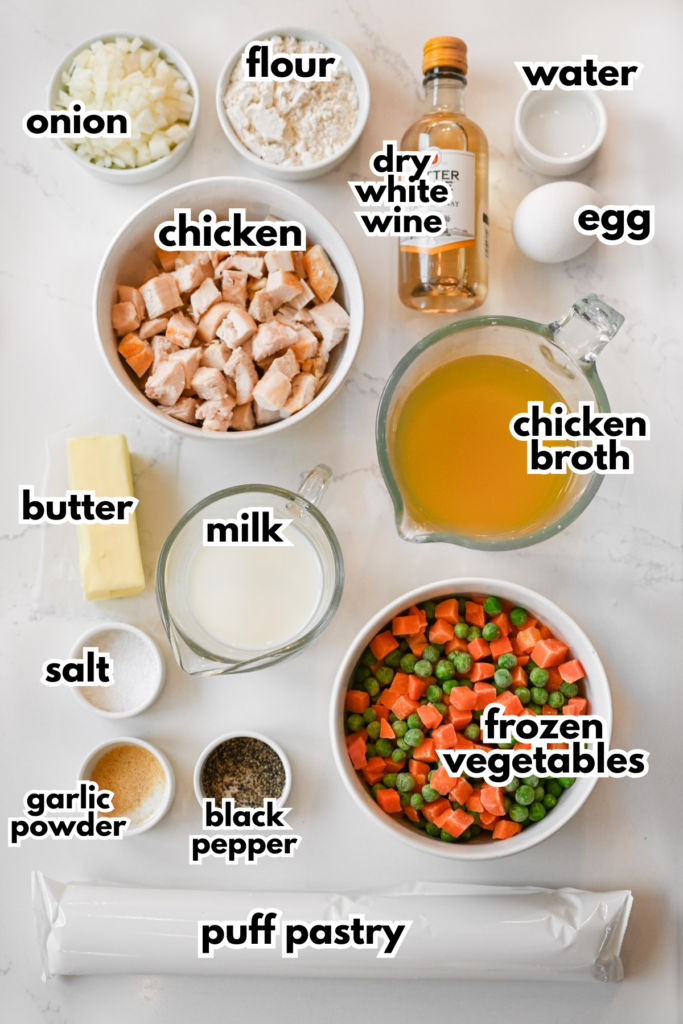 The ingredients needed to make chicken pot pie with puff pastry laid out on a white countertop.