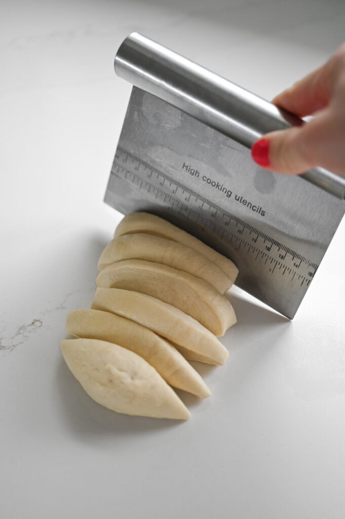 A kitchen counter scraper cutting a chunk of dough into pieces.