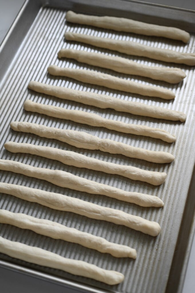 Raw breadsticks on a pan.