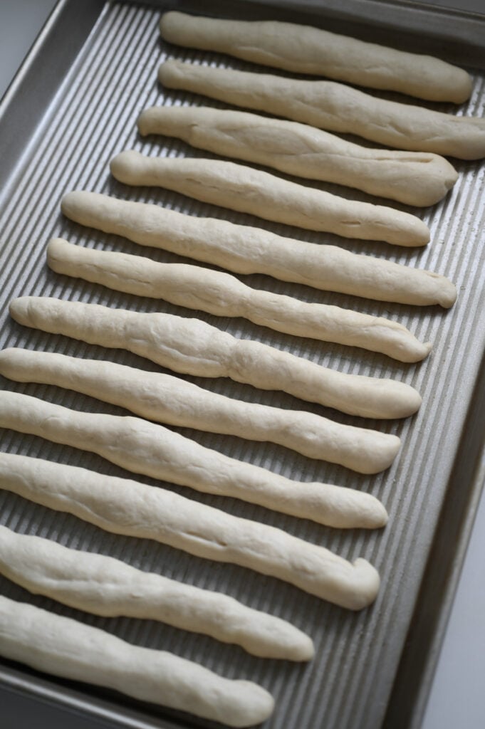 Risen breadsticks on a pan.