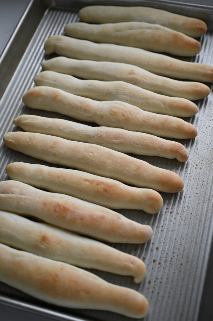 Baked golden brown breadsticks on a pan.