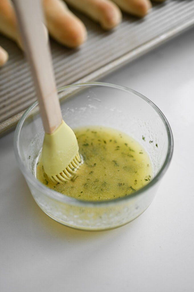 A garlicky butter sauce being stirred by a pastry brush.