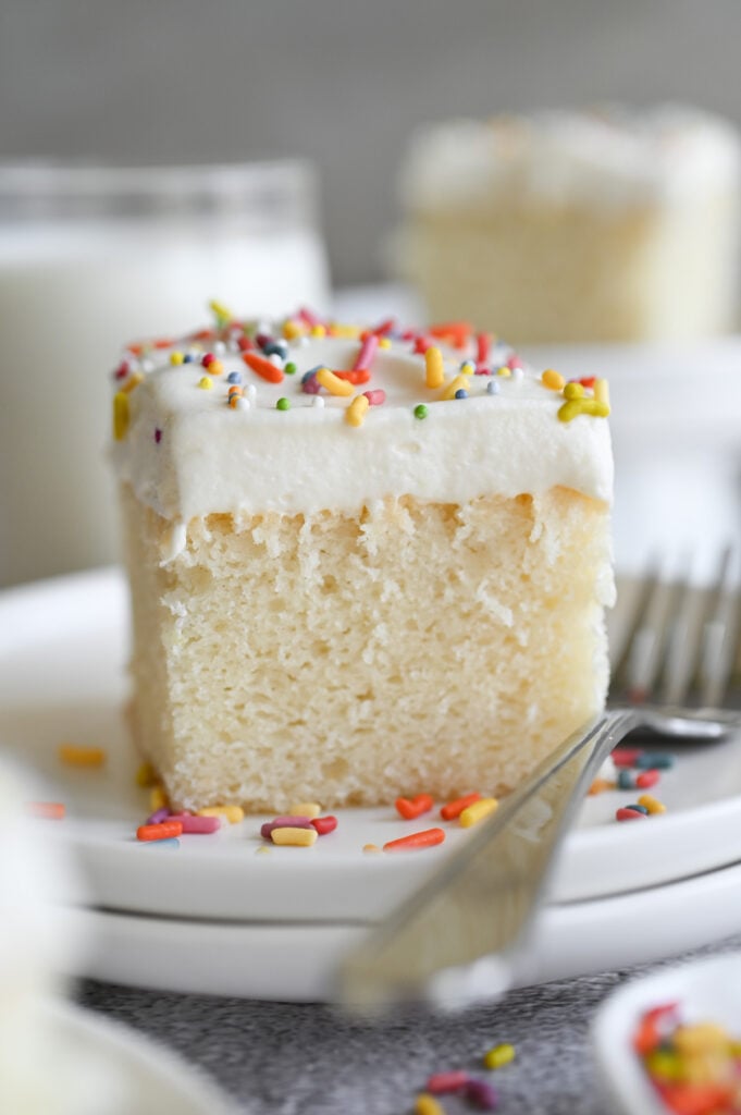 A piece of sheet cake with frosting and colorful sprinkles.