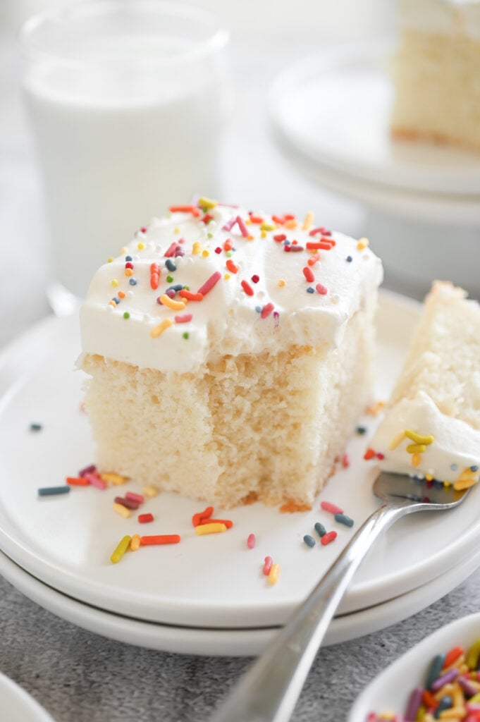 A piece of cake with frosting and sprinkles on top.