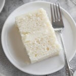 A slice of a 2-layer white cake on a white plate.