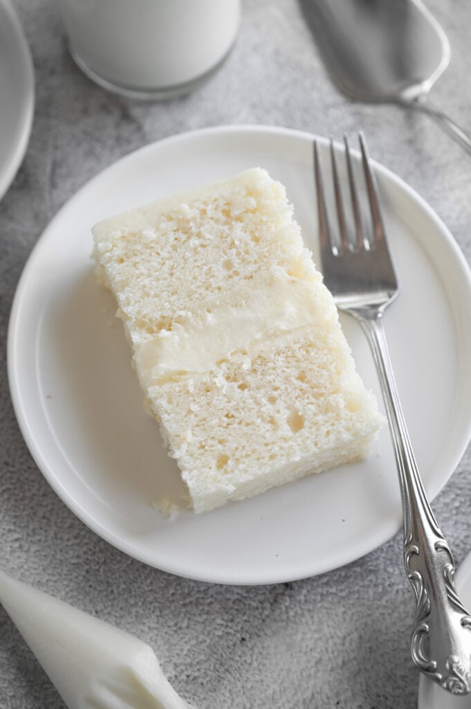 A slice of a 2 layer white cake with vanilla buttercream.
