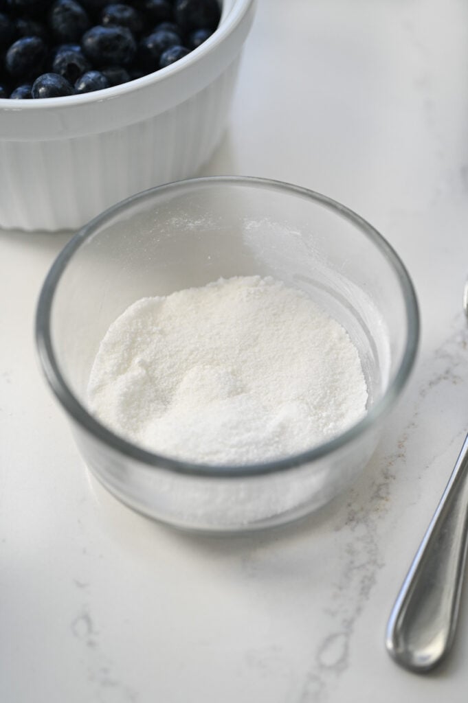 Sugar and cornstarch combined in a small clear glass bowl.