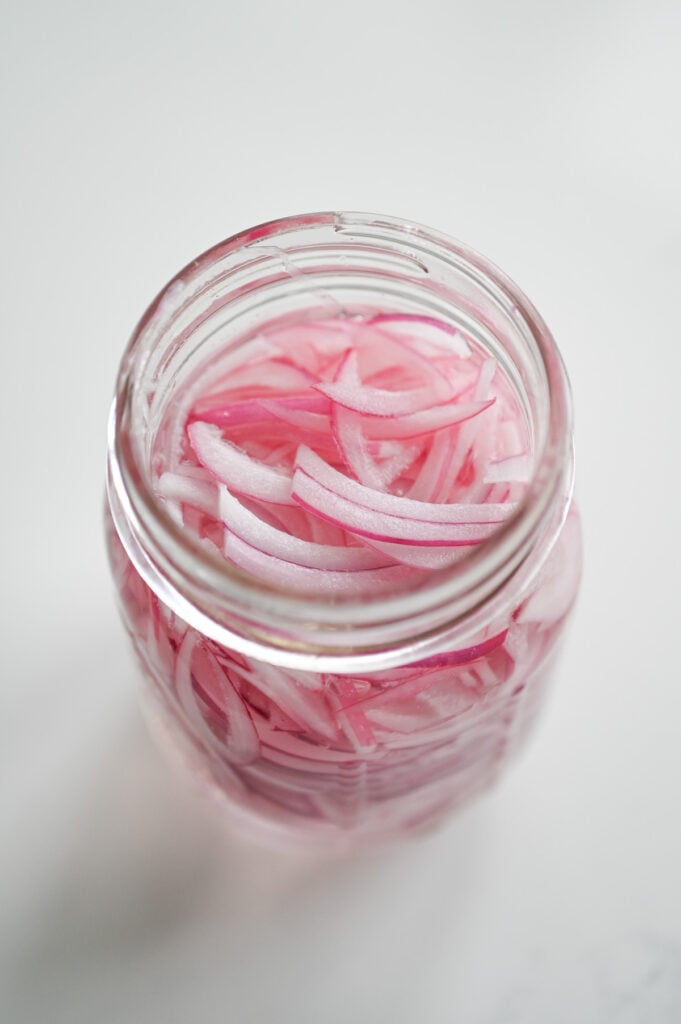 Red onions in a jar with a liquid.