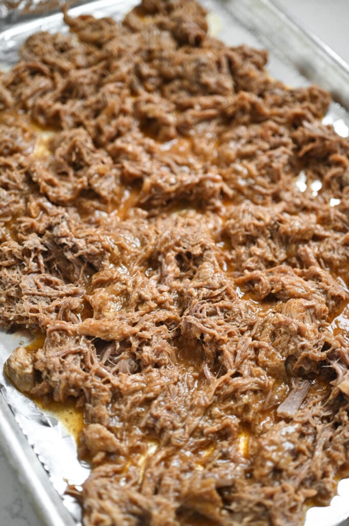 Shredded pork on a foil-lined pan.