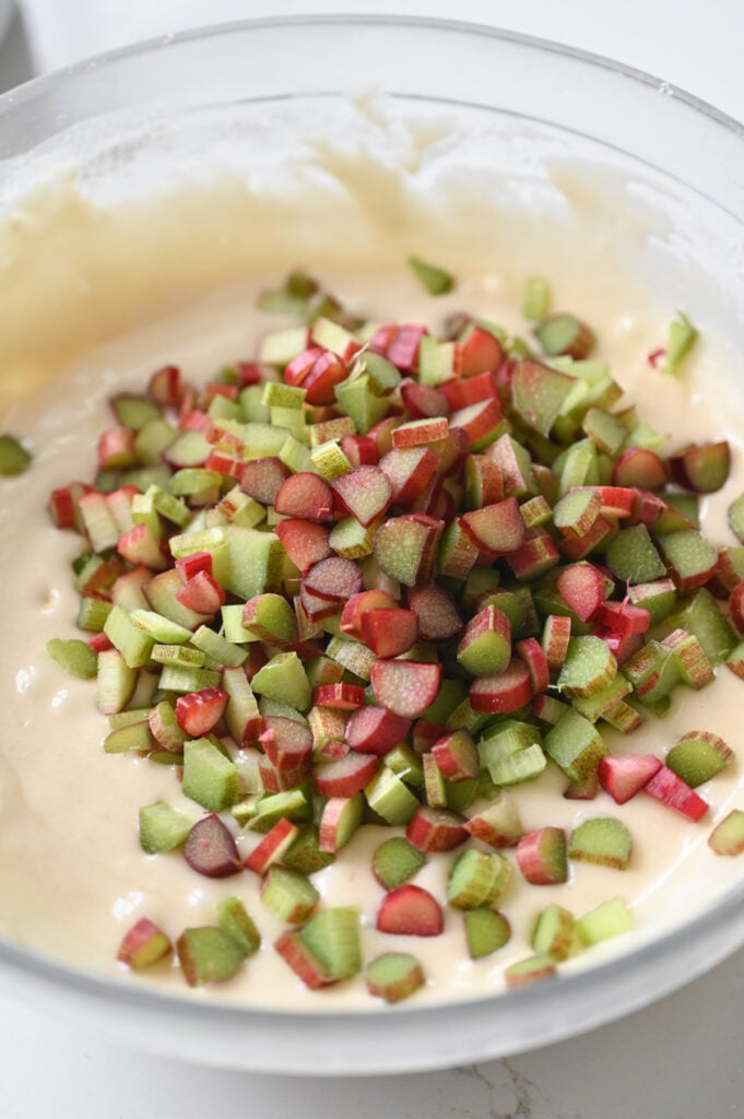 Rhubarb added to a large bowl of batter.