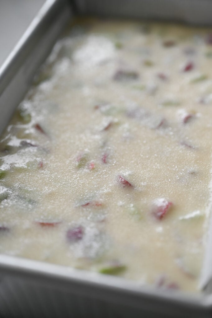 A loaf pan with batter and a sprinkling of granulated sugar on top.