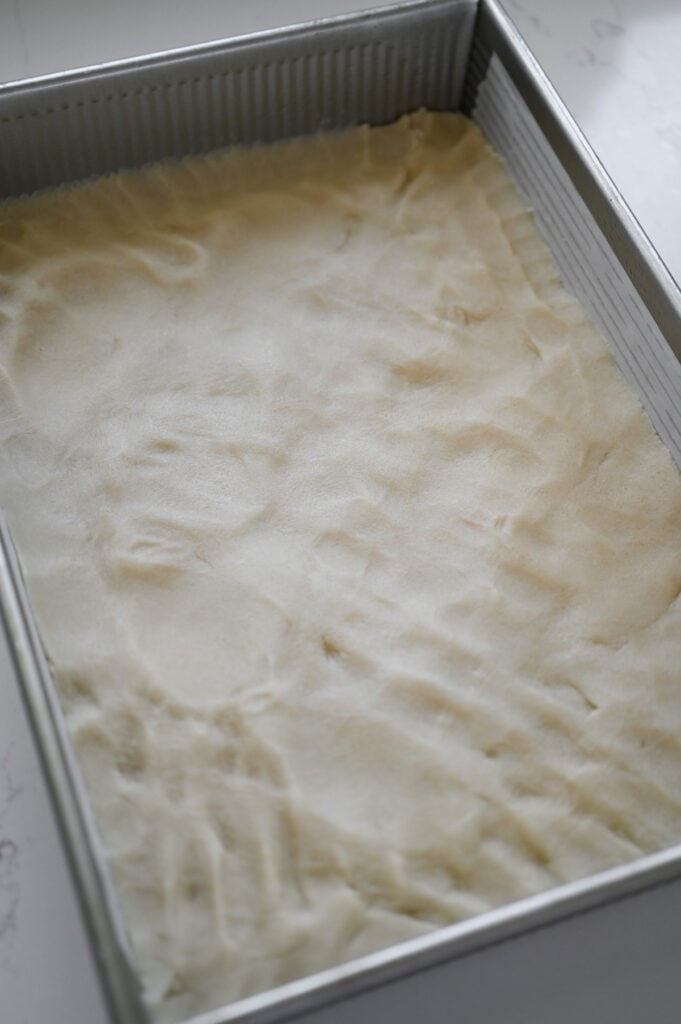 Cookie dough pressed into a 9x13-inch pan.