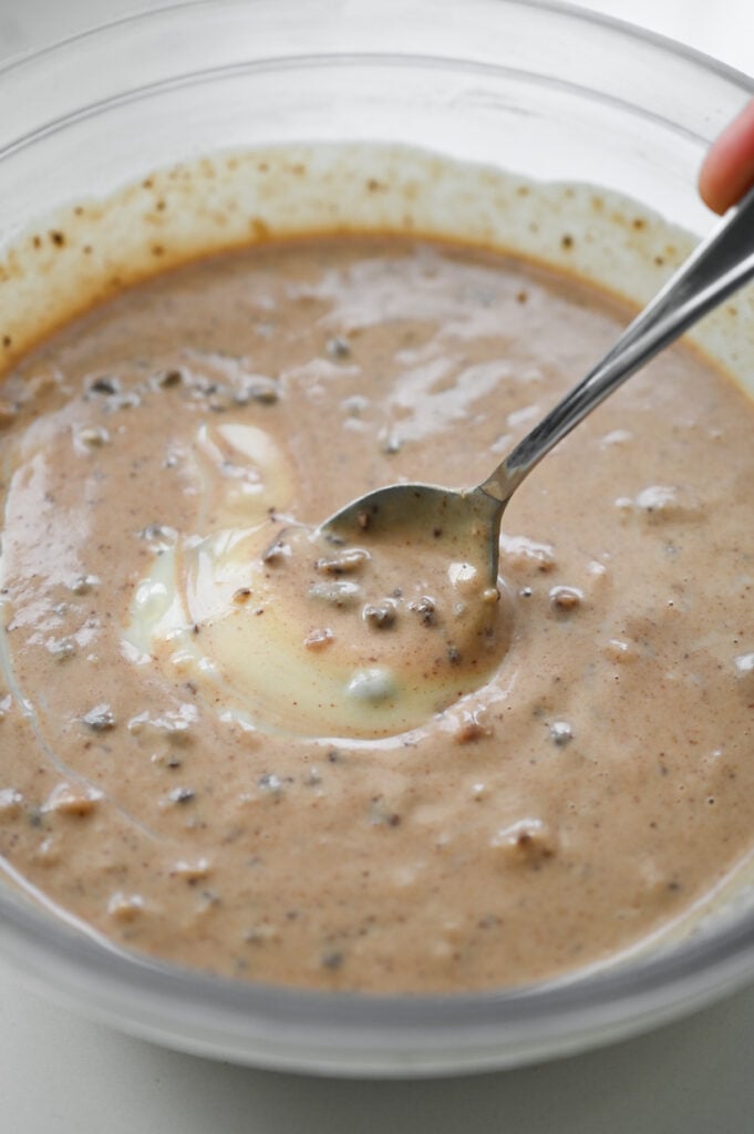 Stirring a chocolate chip filling with sweetened condensed milk in a clear bowl.