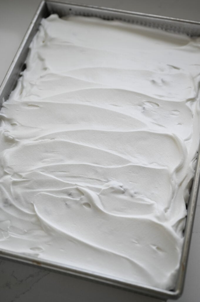 Whipped topping spread onto a dessert in a 9x13 inch pan.